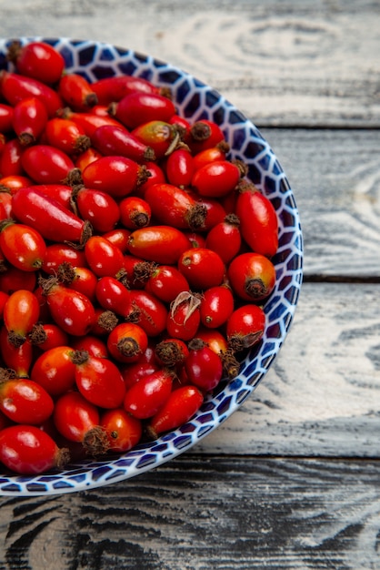 Vista frontal de frutos rojos frescos, bayas maduras y ácidas dentro de la placa en la superficie gris frutas árbol de vitamina color baya