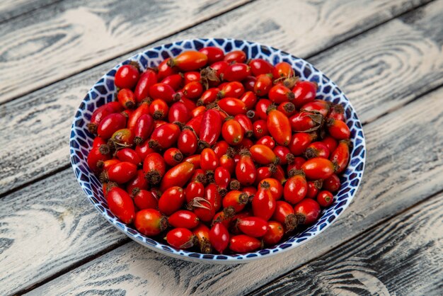 Vista frontal de frutos rojos maduros y bayas ácidas en el escritorio gris de frutas de color baya planta de árbol de vitamina