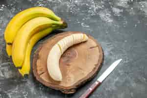 Foto gratuita vista frontal fuente de nutrición paquete de plátanos frescos y picados en un cuchillo de tabla de cortar de madera sobre fondo gris