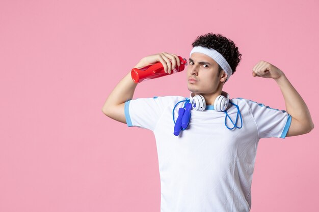 Vista frontal fuerte atleta masculino en ropa deportiva con botella de agua