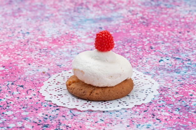 Vista frontal de galleta con crema en la superficie coloreada