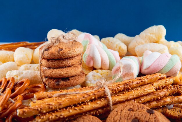 Vista frontal galletas de avena con chocolate en un montón con palitos de pan bagels y copos de maíz