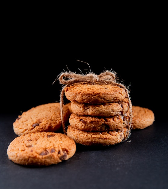 Vista frontal de galletas de avena con chocolate sobre un fondo negro