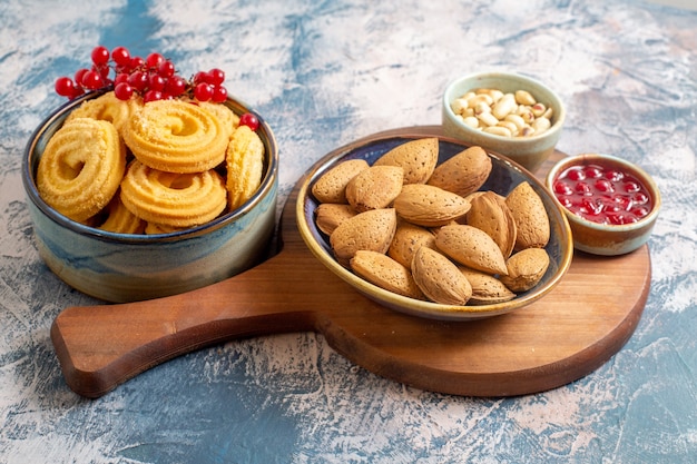 Vista frontal de las galletas de azúcar con nueces y mermelada en superficie ligera