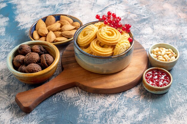 Vista frontal de las galletas de azúcar con nueces y mermelada en superficie ligera