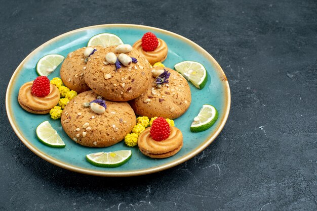 Vista frontal de las galletas de azúcar con rodajas de limón fresco en la superficie gris pastel galleta galleta pastel dulce