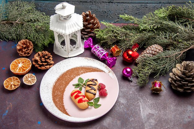 Vista frontal de galletas dulces con árbol de navidad y juguetes en el espacio oscuro