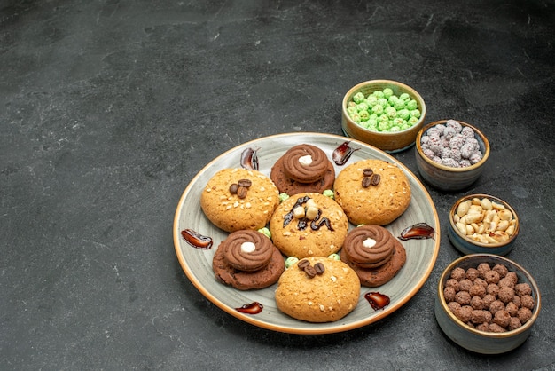 Vista frontal de galletas dulces con caramelos en el espacio gris