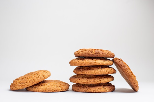 Vista frontal de las galletas dulces en las galletas de escritorio blanco postre de azúcar foto de té pastel