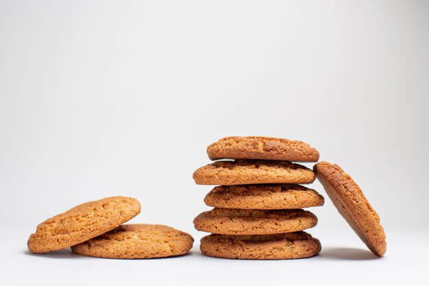 Vista frontal de las galletas dulces en las galletas de escritorio blanco postre de azúcar foto de té pastel