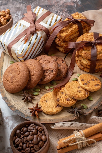 Vista frontal de galletas dulces con nueces y presenta sobre fondo claro pastel de té de azúcar de color pastel dulce pastelería