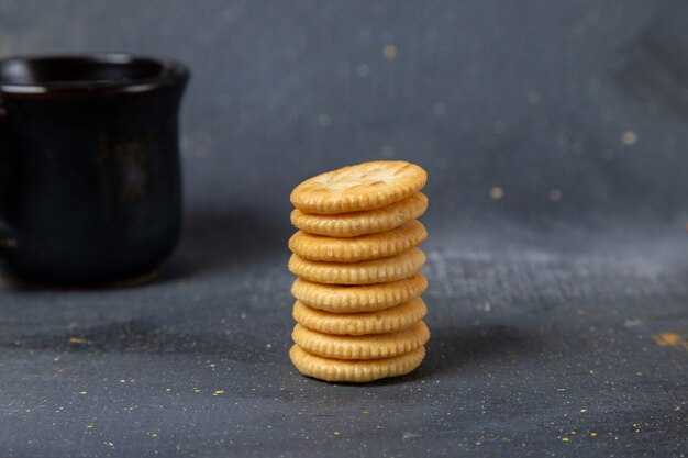 Vista frontal galletas dulces redondas con taza de leche negra sobre gris