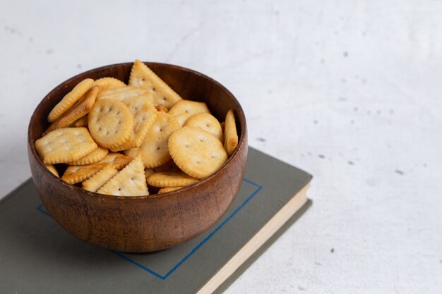 Vista frontal de las galletas saladas dentro del recipiente redondo marrón en el cuaderno