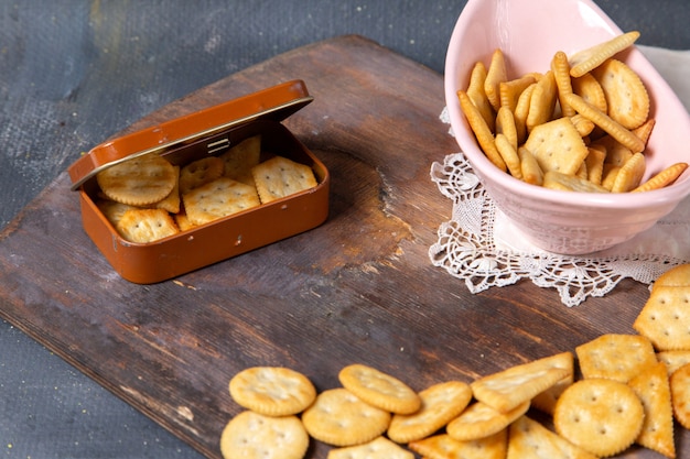 Vista frontal de galletas saladas en un escritorio de madera y gris