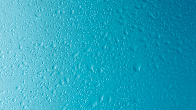 Vista frontal de la gota de agua sobre una superficie clara