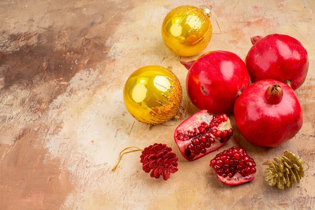 Vista frontal de granadas frescas con juguetes de árbol de navidad sobre fondo claro foto en color jugo de frutas suave