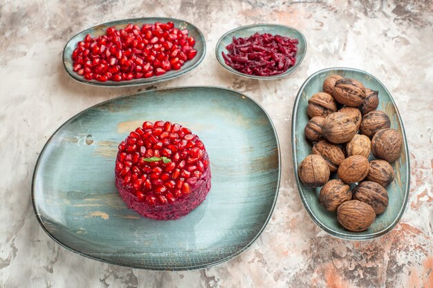 Vista frontal de granadas frescas con nueces en la luz de la foto de la salud del color de la fruta tuerca