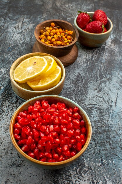 Vista frontal de las granadas peladas con otras frutas en la mesa de luz oscura fruta fresca de color