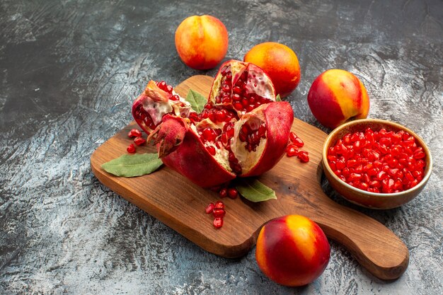 Vista frontal de granadas en rodajas con melocotones en el color fresco del árbol frutal de la mesa oscura