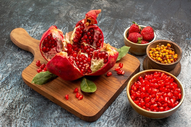 Vista frontal de granadas en rodajas con otras frutas en la mesa de luz color fruta fresca