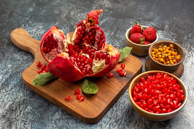 Vista frontal de granadas en rodajas con otras frutas en la mesa de luz color fruta fresca
