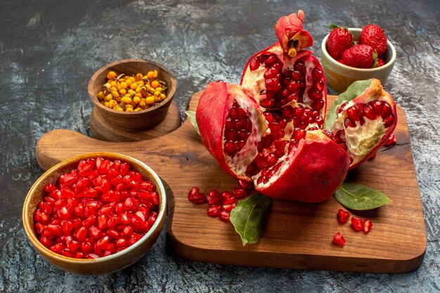 Vista frontal de granadas en rodajas con otras frutas en la mesa de luz color fruta fresca