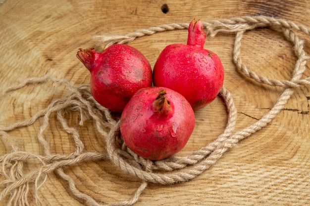 Vista frontal de granadas rojas con cuerdas en un escritorio de madera árbol de jugo de fruta de color
