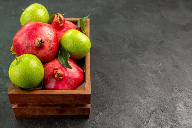 Vista frontal de granadas rojas frescas con manzanas verdes en el color de la fruta madura de escritorio oscuro