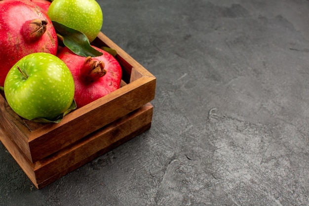 Vista frontal de granadas rojas frescas con manzanas verdes en el color de la fruta madura del piso oscuro