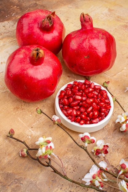 Vista frontal granadas rojas frescas peladas y con frutas enteras sobre fondo marrón foto de fruta de color jugo suave