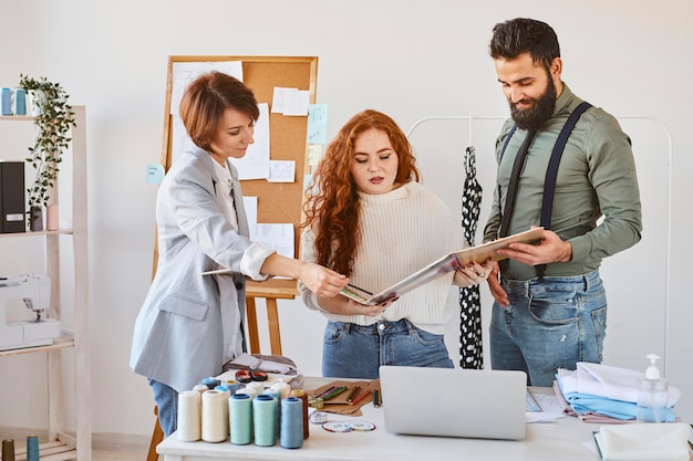 Vista frontal del grupo de tres diseñadores de moda que trabajan en atelier con paleta de colores