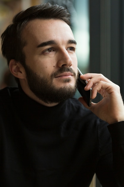 Vista frontal guapo hombre hablando por teléfono