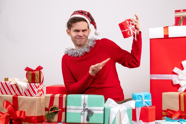 Vista frontal guapo con sombrero snata sentado alrededor de regalos de navidad