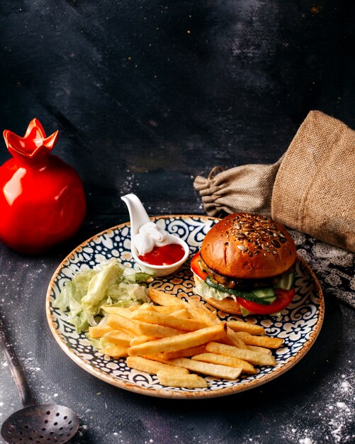 Vista frontal hamburguesa junto con papas fritas en la superficie gris