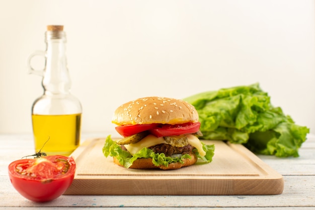 Vista frontal de una hamburguesa de pollo con queso y ensalada verde junto con aceite de oliva en el escritorio de madera y comida rápida de sándwich