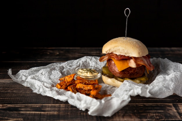 Vista frontal hamburguesa con queso y batatas fritas con salsa