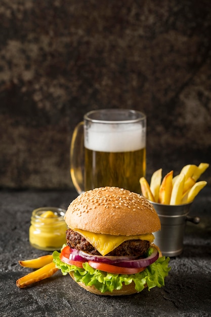 Vista frontal de la hamburguesa de ternera, papas fritas y salsa con cerveza y espacio de copia