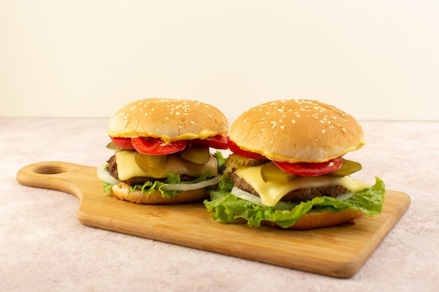 Una vista frontal de hamburguesas de carne con verduras y ensalada verde en la mesa de madera