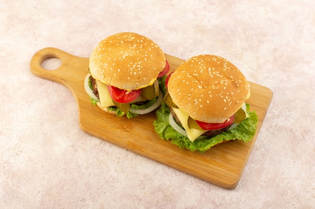 Una vista frontal de hamburguesas de carne con verduras y ensalada verde en la mesa de madera