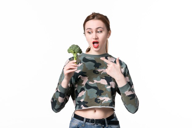 Vista frontal hembra joven con brócoli verde sobre blanco