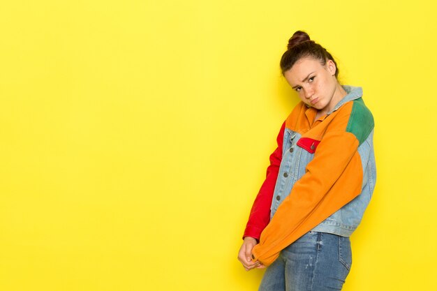 Una vista frontal hembra joven en camisa amarilla chaqueta colorida y blue jeans entristecido