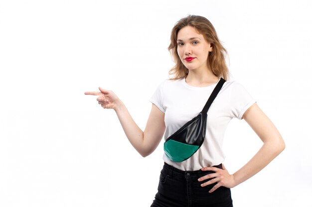 Una vista frontal hembra joven en camiseta blanca y jeans negros con bolsita en el blanco