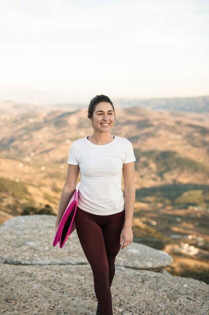 Vista frontal hembra joven con colchoneta de yoga