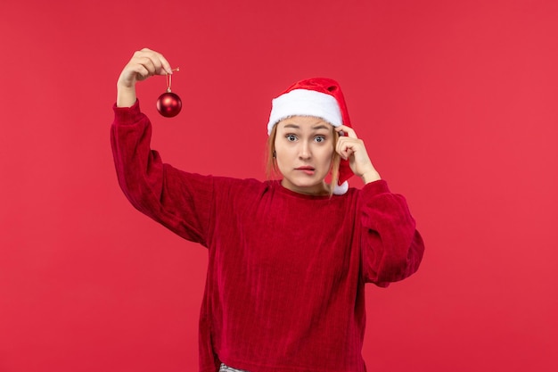 Vista frontal hembra regular sosteniendo juguetes navideños, vacaciones navideñas rojas