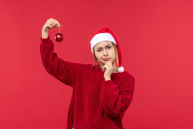 Vista frontal hembra regular sosteniendo juguetes navideños, vacaciones navideñas rojas