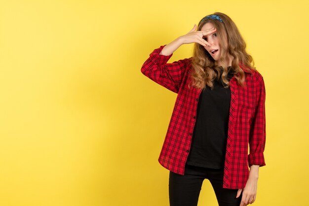 Vista frontal de las hembras jóvenes en camisa a cuadros roja sólo de pie y posando sobre fondo amarillo modelo niña mujer color emociones humanas