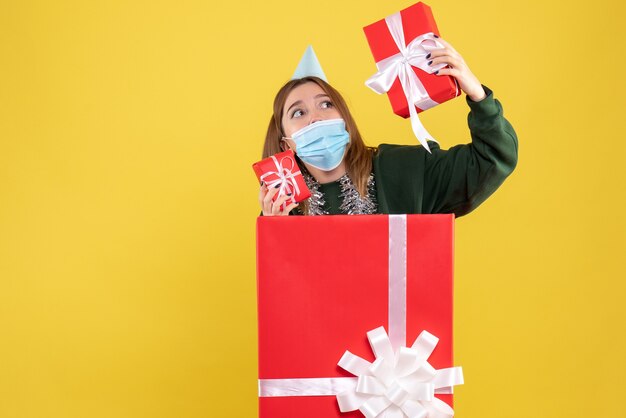 Vista frontal de las hembras jóvenes dentro de la caja actual en máscara estéril con regalos