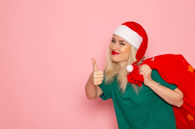 Foto gratuita vista frontal de las hembras jóvenes que llevan bolsa roja con regalos en la pared rosa modelo de vacaciones navidad año nuevo foto en color santa