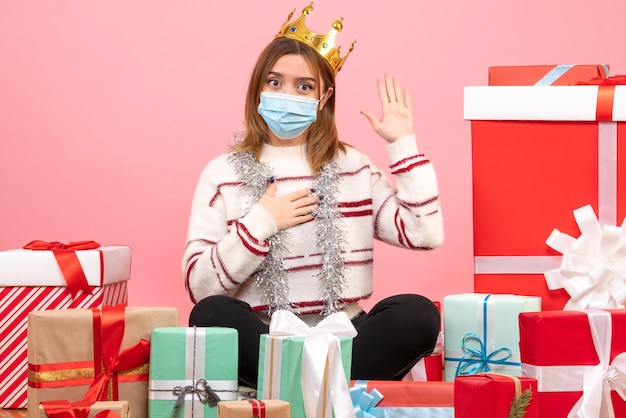 Vista frontal de las hembras jóvenes sentados alrededor de los regalos de Navidad en máscara estéril