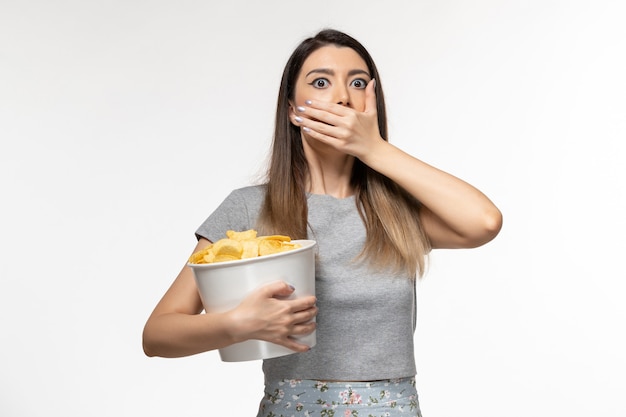 Vista frontal de las hembras jóvenes sosteniendo papas fritas mientras ve la película en el escritorio blanco